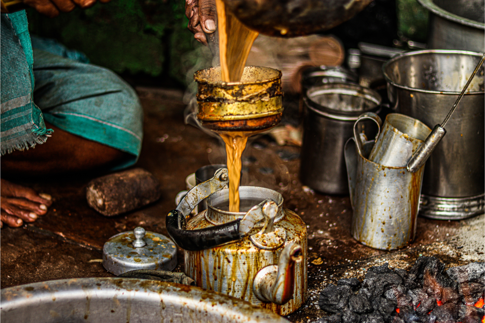 Homme indien préparant et versant du chai traditionnel sur du charbon